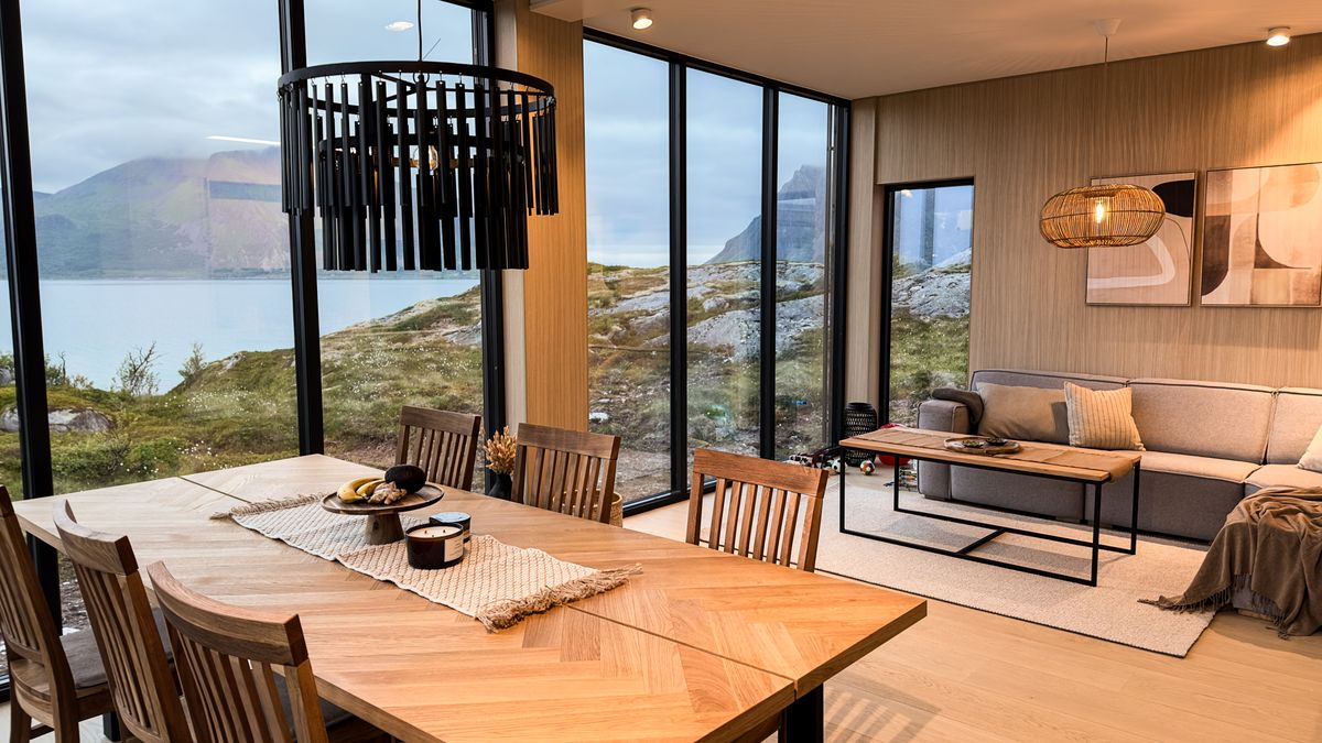 Open living and dining room in Lyngvær with a panoramic window onto the sea