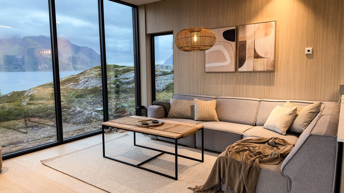 Corner sofa and coffee table in the Lyngvær lounge, sea and mountains through the windows