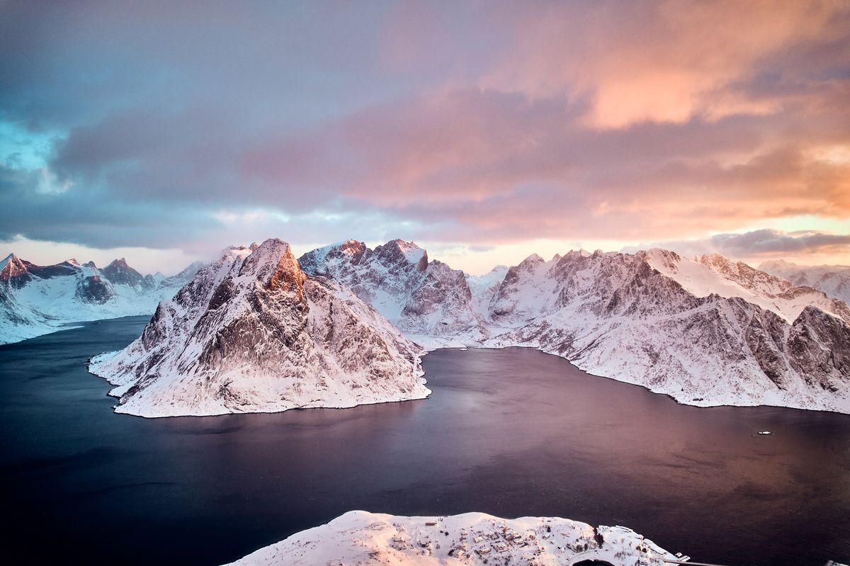 Snowy peaks and small islands near Reine in soft pink evening light